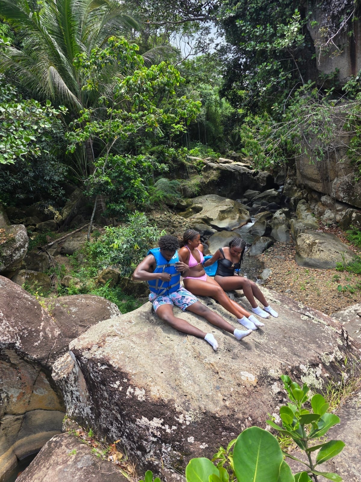 Manny's Tours clients relaxing on rocks by a jungle stream — the hidden spots only locals know