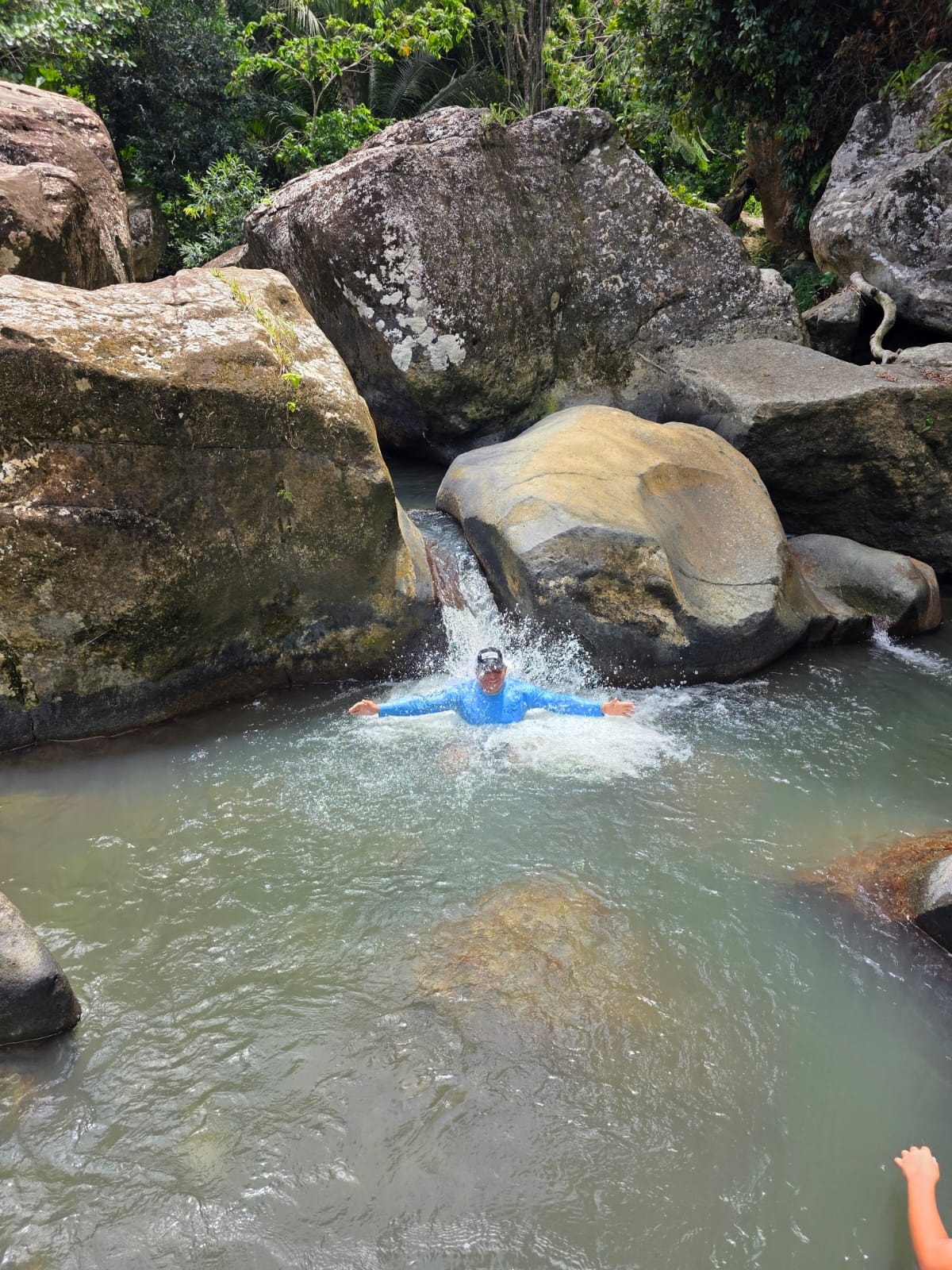 Happy client swimming under a natural waterfall deep in El Yunque rainforest