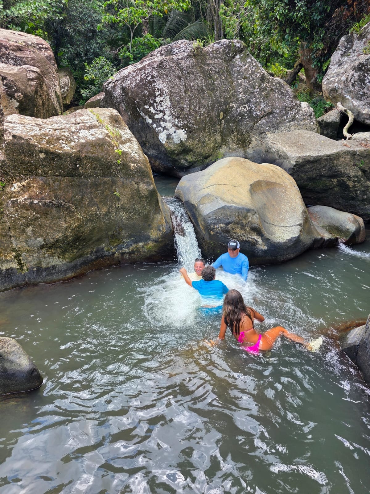 Family swimming together in a natural waterfall pool — memories that last a lifetime