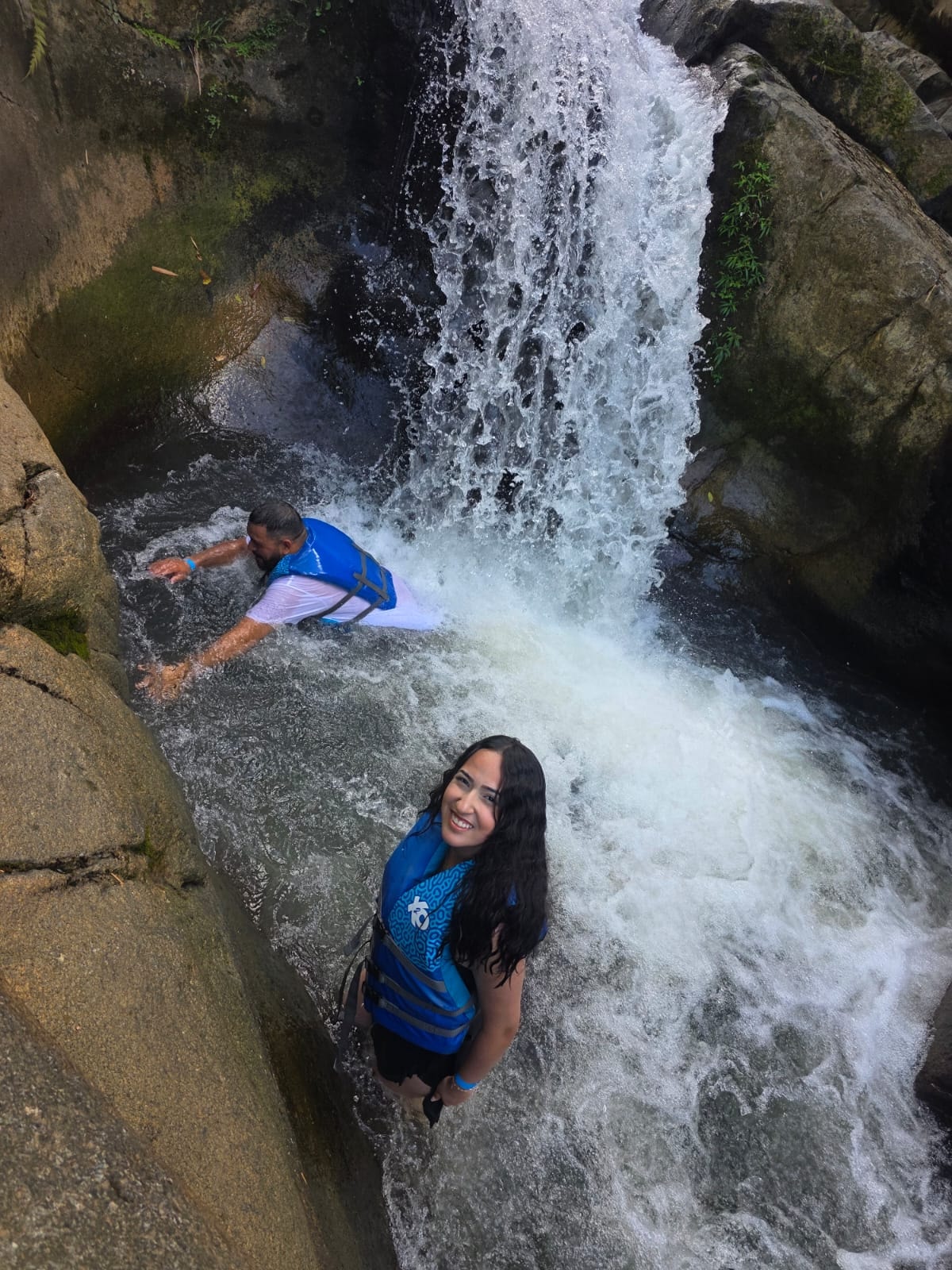 Guest smiling ear to ear at the base of a roaring waterfall — this is what Puerto Rico really looks like