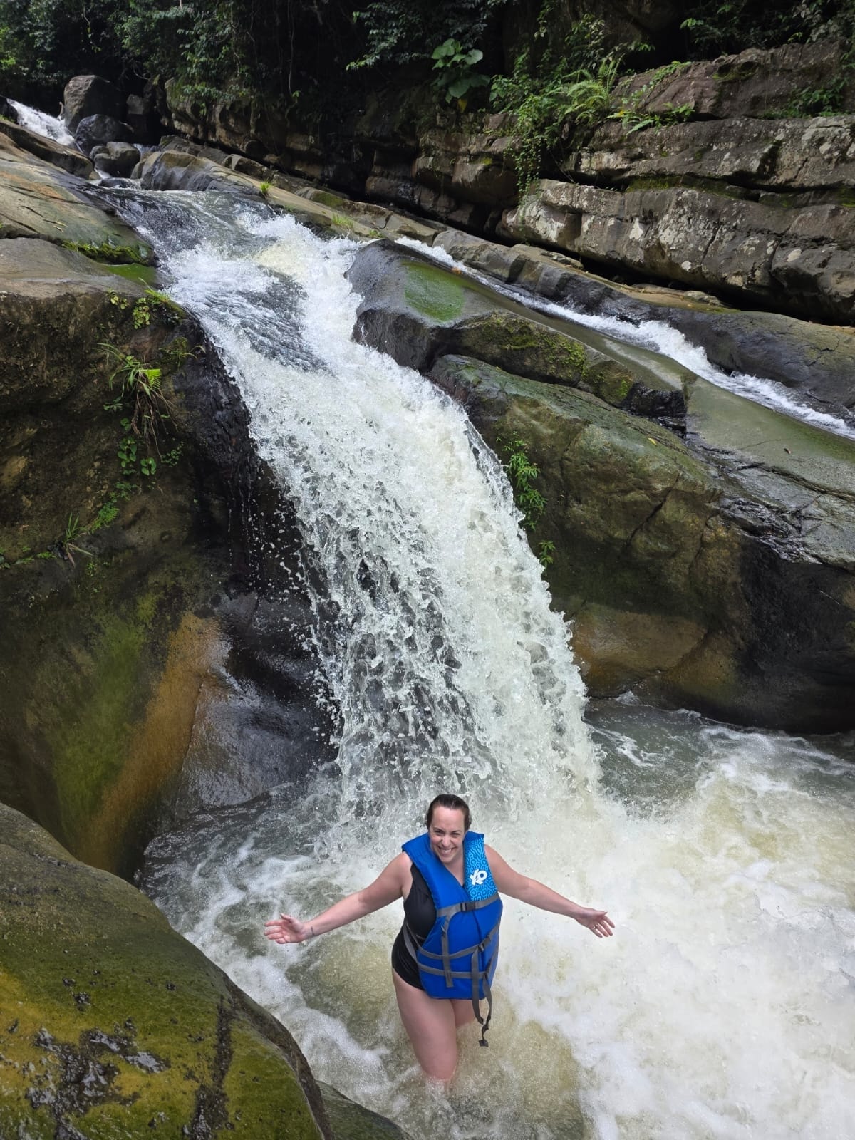 Guests laughing and splashing at the base of a powerful waterfall in El Yunque — pure joy on a Manny's Tours adventure